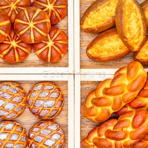 Puede incluir: Vista aérea de varios productos de panadería, incluyendo panes redondos, en forma de estrella y trenzados. Los panes son de color marrón dorado con diseños intrincados, exhibidos en compartimentos de madera. Una deliciosa variedad de productos horneados.