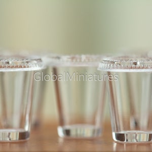 May include: Four clear plastic cups with lids, arranged in a row on a wooden surface. The cups are empty and appear to be made of a thin, transparent plastic.