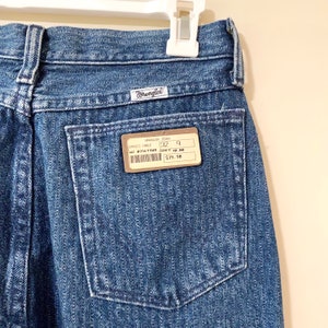 May include: A pair of blue denim Wrangler jeans with a brown price tag that reads "Wrangler Jeans, Original Chele, 32, 9, 41J 8356794R, $39.98".