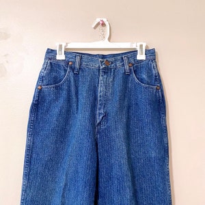 May include: A pair of high-waisted, light blue denim jeans with a straight leg fit. The jeans have a classic five-pocket design and a button fly.