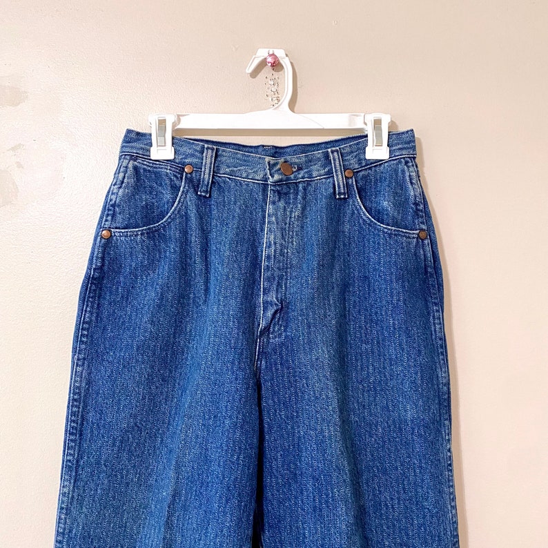 May include: A pair of high-waisted, light blue denim jeans with a straight leg fit. The jeans have a classic five-pocket design and a button fly.