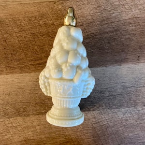 May include: White porcelain bottle shaped like a fruit basket with a gold top. The bottle is filled with molded fruit and has a detailed base.