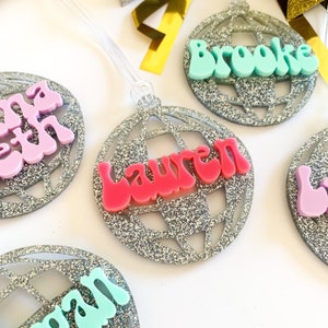 May include: Silver glitter disco ball ornaments with names "Lauren", "Brooke", "Beth", and "Morgan" written in colorful, retro-style letters.