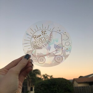 May include: A clear iridescent sticker with a gold outline of a roller skate and the text "Rise & Grind".