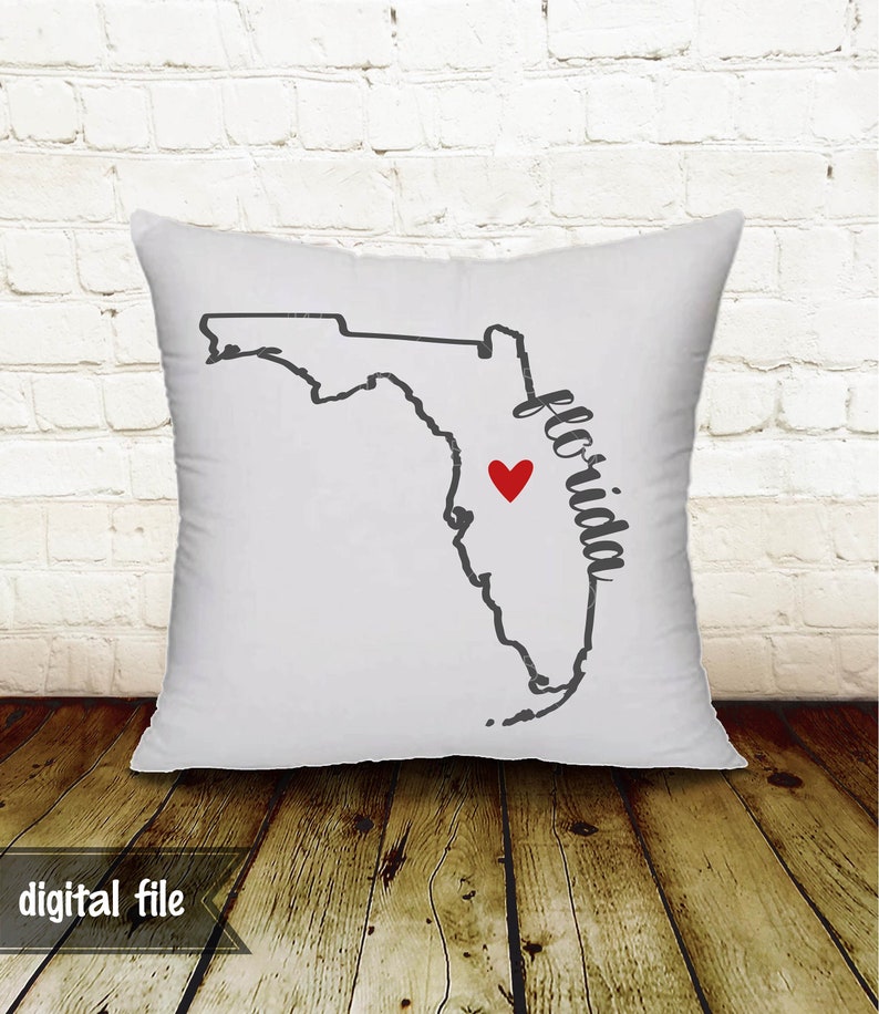 May include: White square pillow featuring a black outline of the state of Florida with a red heart marking a location. The word "Florida" is written in a script font. The words "digital file" are at the bottom.
