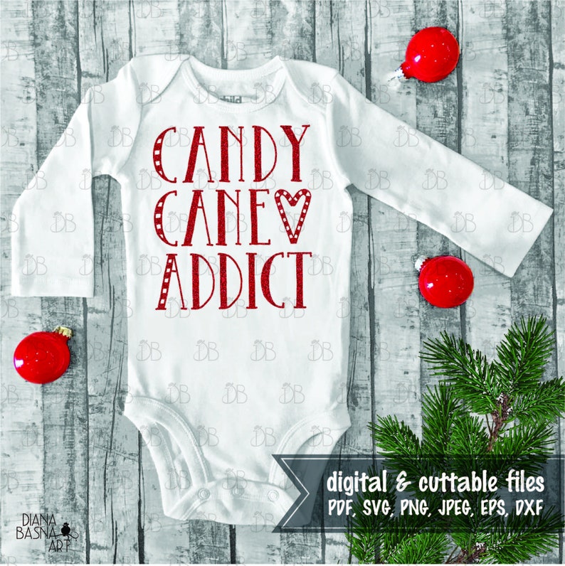 Peut inclure: Combinaison blanche &agrave; manches longues avec un texte rouge qui dit "Candy Cane Addict" avec un c&oelig;ur rouge en forme de canne &agrave; sucre. La combinaison est sur un fond en bois avec des boules de No&euml;l rouges et une branche de pin.