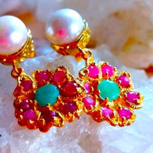 Può includere: Un paio di orecchini d'oro con un ciondolo di perle e un ciondolo a forma di fiore con pietre preziose rosa e verdi.