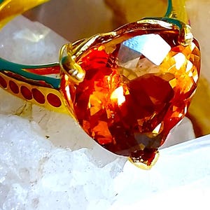 Ładny pierścionek w kształcie serca, rozmiar 6 1/4, o wymiarach 13 x 10 mm. Naturalny topaz imperialny i rubin, platerowany srebrem próby 925 w kolorze złotym.