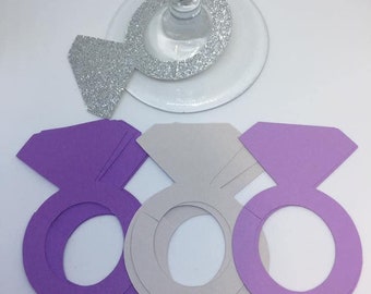 May include: Set of six purple and gray paper ring-shaped drink markers. The markers are shaped like a diamond ring with a large center stone.