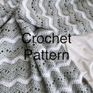 May include: A crochet blanket with a wavy pattern in shades of gray and white. The blanket is folded and the text "Crochet Pattern" is visible in the center of the image.