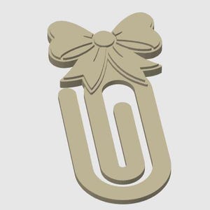 May include: A beige paperclip with a bow design at the top. The bow has detailed lines and a circular center. The paperclip is a U-shape with a rounded bottom. The design is simple and elegant.
