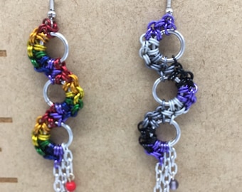 May include: A pair of dangle earrings with a chain and beads. One earring is rainbow coloured and the other is black, white, and purple.