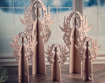 May include: Set of five wooden angel ornaments in various sizes. The angels are intricately carved with a delicate lace-like design and have a light brown finish.