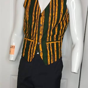 Pode incluir: Um colete listrado verde e amarelo com decote em V, combinado com calças pretas. O colete apresenta uma frente abotoada e um padrão semelhante ao bambu. A roupa é exibida em um manequim.