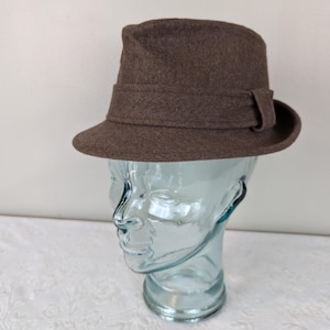 May include: A brown felt fedora hat with a wide brim and a brown grosgrain ribbon band.