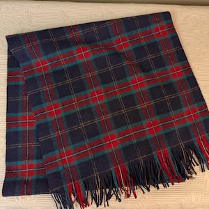 May include: A navy blue plaid throw blanket with red, green, and gold accents. The blanket has a fringe border.