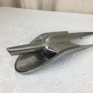 May include: A chrome car bonnet ornament in the shape of a bird with wings spread out. The ornament is in good condition with some minor wear and tear.