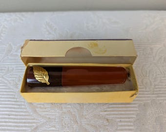 Peut inclure: Un stylo vintage dans une boîte jaune. Le stylo est marron avec un accent de feuille d'or. La boîte est ouverte, révélant le stylo à l'intérieur. Le stylo a un dessus marron foncé et un corps marron plus clair.