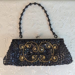 Cartera estilo clutch vintage con asa de cuentas a juego, cuentas negras y doradas y lentejuelas sobre un cuerpo de satén negro. Sin marca del fabricante 04893