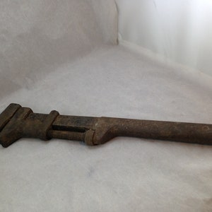 May include: A rusty, old adjustable wrench with a long, wooden handle.