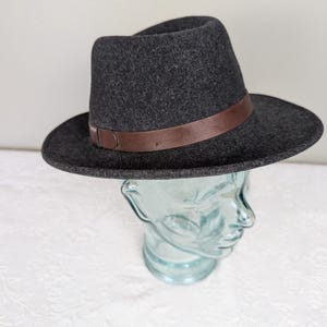 May include: A gray felt fedora hat with a brown leather band.