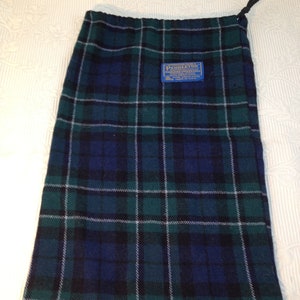 May include: A green, blue, and white plaid drawstring bag with a Pendleton label. The label reads "Pendleton Woolen Mills, Portland, Oregon, USA, Virgin Wool, Made in USA".