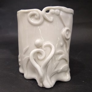 May include: White ceramic vase with a decorative, raised design of swirling vines and leaves.