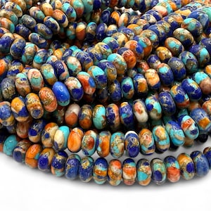 May include: Close-up of a strand of colorful gemstone beads. The beads are oval-shaped and feature a mix of blue, orange, turquoise, and gold colors. The beads are strung together, creating a textured and vibrant appearance. Ideal for jewelry making.