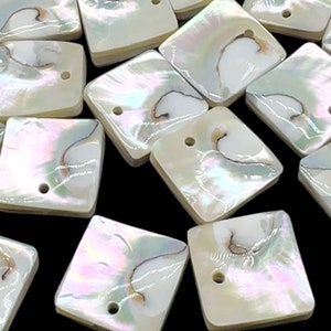 May include: Close-up of square, iridescent mother-of-pearl beads with a hole for stringing. The beads have a pearlescent sheen with brown and cream-colored markings. The beads are ideal for jewelry making.