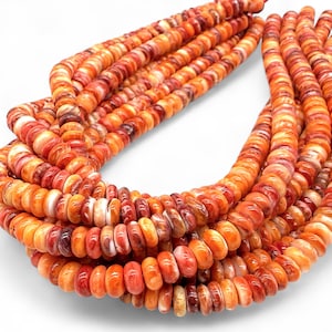 May include: Strands of orange and red spiny oyster shell beads. The beads are oval-shaped and vary in size, creating a textured and layered effect. The colors range from light orange to deep red, with some beads showing a mix of hues.