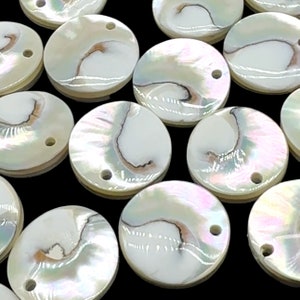 May include: A collection of white iridescent round shell buttons with a hole in the center. The buttons have a natural, organic look and are perfect for adding a touch of elegance to any project.