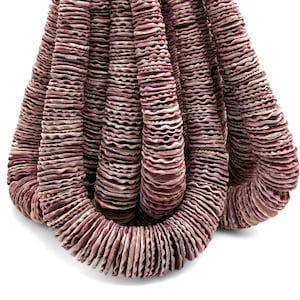 May include: A decorative hanging ornament composed of numerous small, circular, ruffled purple shells strung together in multiple vertical strands that drape downward, creating a dense, textured, and layered appearance with a consistent color.