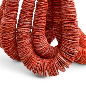 May include: A long strand of small, circular, terracotta-colored discs with wavy, scalloped edges. The discs are strung together in a dense, continuous loop, creating a textured, repetitive pattern of warm, earthy orange-red tones throughout.