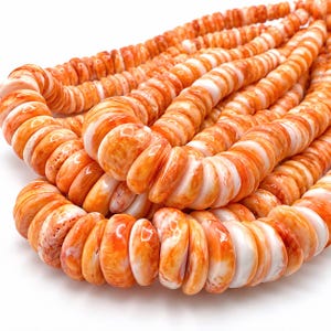 May include: A strand of flat, round beads featuring a marbled pattern of vibrant orange and opaque white. The beads are arranged in a dense, layered formation, showcasing a smooth, polished texture and consistent circular shape throughout.