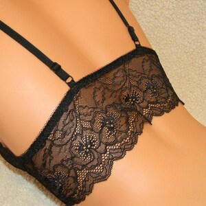 May include: Black lace lingerie top with adjustable straps. The top has a delicate floral pattern and a scalloped edge.