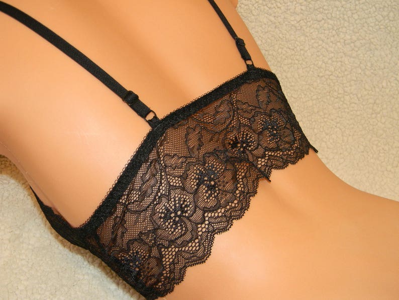 May include: Black lace lingerie top with adjustable straps. The top has a delicate floral pattern and a scalloped edge.