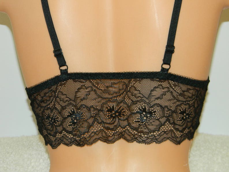 May include: Black lace bralette with adjustable straps. The bralette has a delicate floral pattern and is made of soft, stretchy lace.
