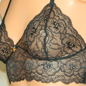 May include: Black lace bralette with a delicate floral pattern. The bralette has adjustable straps and a clasp closure in the back.