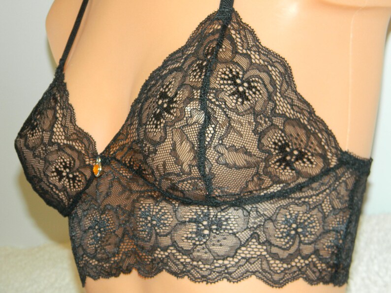 May include: Black lace bralette with a delicate floral pattern. The bralette has adjustable straps and a clasp closure in the back.