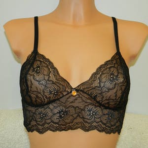 May include: Black lace bralette with adjustable straps and a small gold-toned embellishment in the center.