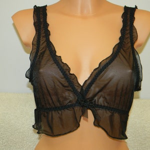 Könnte beinhalten: Schwarzes, durchsichtiges Oberteil aus Spitze mit Rüschenbesatz und Schleife.