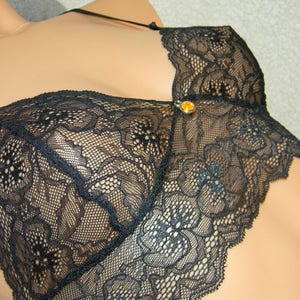 May include: Black lace lingerie top with a small gold-colored accent.
