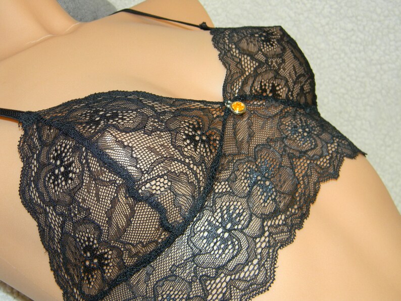 May include: Black lace lingerie top with a small gold-colored accent.