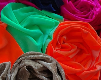 May include: A collection of fabric swatches in various colours, including pink, green, orange, brown, and blue. The fabrics are arranged in a circular pattern, with the edges of each swatch overlapping.