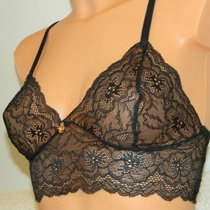 May include: Black lace bralette with adjustable straps. The bralette has a delicate floral pattern and a scalloped edge.