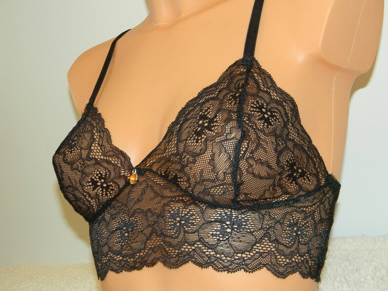 May include: Black lace bralette with adjustable straps. The bralette has a delicate floral pattern and a scalloped edge.
