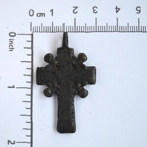 May include: A black metal cross pendant with a decorative design. The cross is about 2 inches tall.