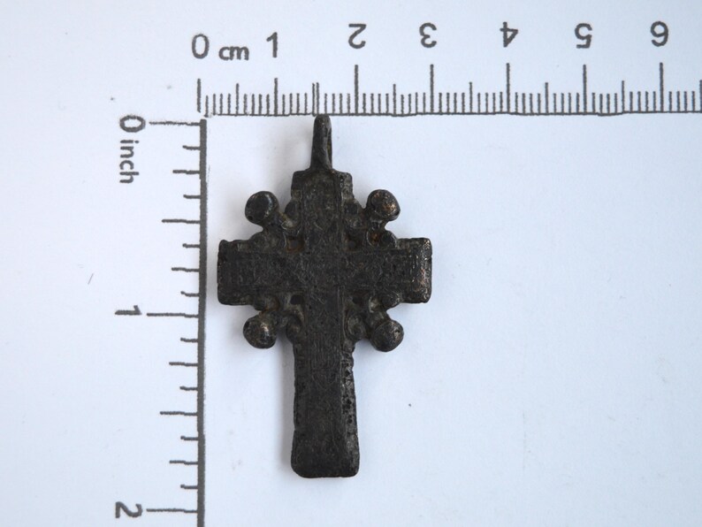 May include: A black metal cross pendant with a decorative design. The cross is about 2 inches tall.