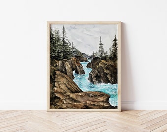 May include: Watercolor painting of a rocky coastline with a turquoise ocean and dark green trees. The painting is framed in a light wood frame.