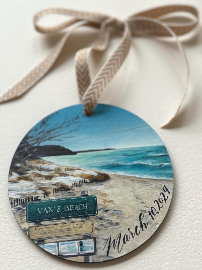 May include: A round wooden ornament featuring a painted scene of a beach with a sign that reads "Van's Beach" and the date "March 10, 2024".